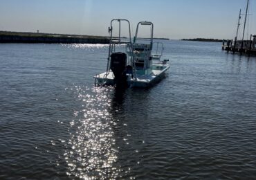Photo of sunny day with fishing boat floating away from marina.