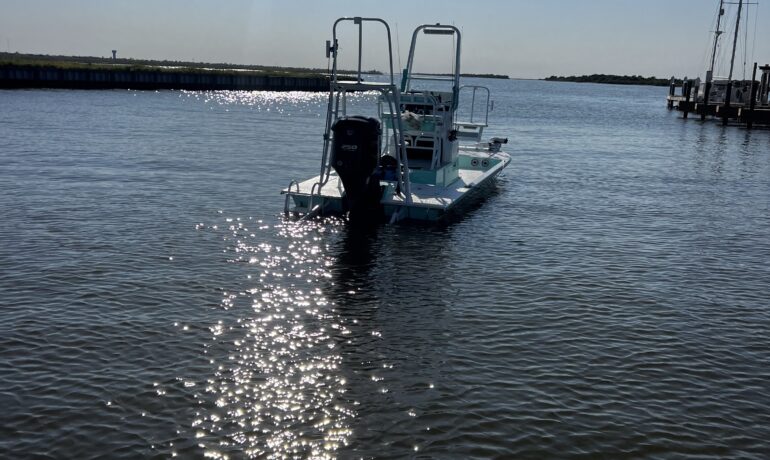 Photo of sunny day with fishing boat floating away from marina.